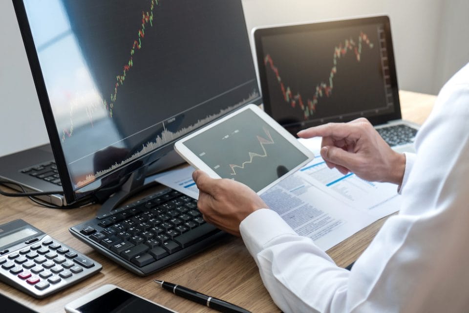 Stock exchange market concept, stock broker looking at graph working and analyzing with display screen, pointing on the data presented and deal on a exchange, Businessman trading stocks online.