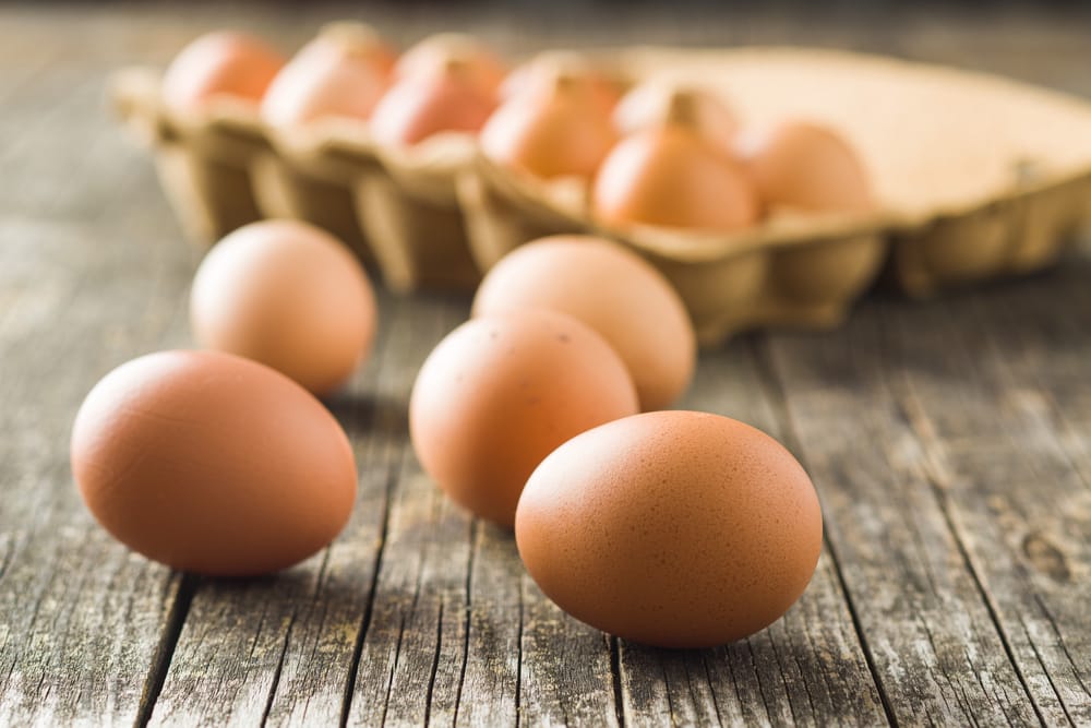 Raw chicken eggs on old wooden table.