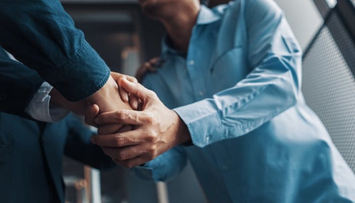 Two men using both hands each to shake hands.