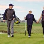 A happy family playing a round of golf together and creating loving memories for their young child.