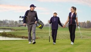 A happy family playing a round of golf together and creating loving memories for their young child.