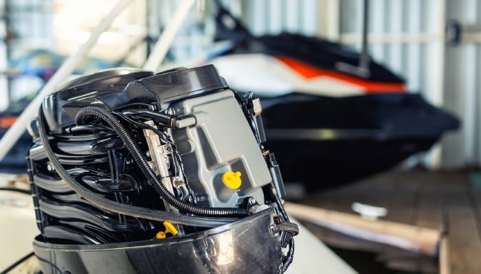 Technician repairing a motorboat engine, with the vessel's motor cover open for seasonal service and maintenance.