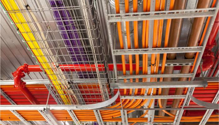 Several organized cable trays are attached to the ceiling. They contain orange, yellow, purple, and white cables.