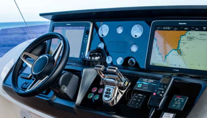 A close-up of a boat's navigation system. The system looks new with one screen showing a map and coordinates.