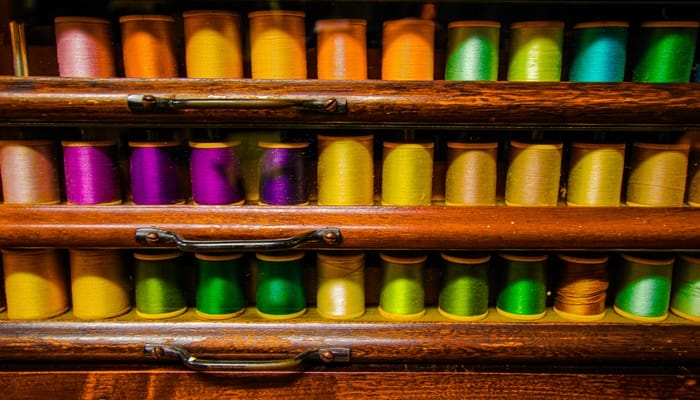A vintage wooden quilting cabinet with perfectly organized spool of thread in a wide variety of colors.
