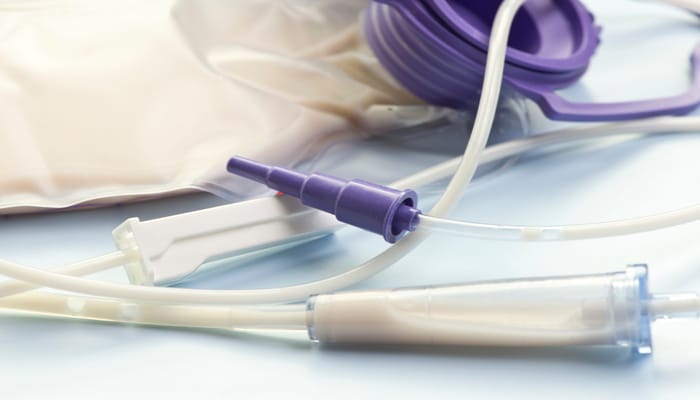 A child's feeding tube with purple external parts and white cords. The feeding liquid sits inside the tube.