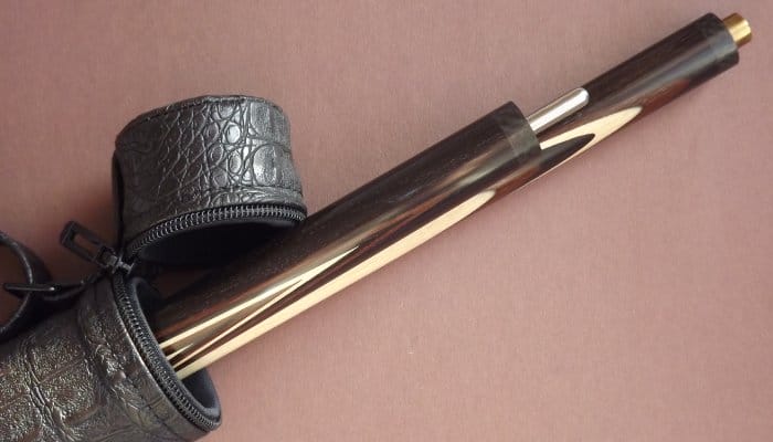 A brown pool cue sticking out of a leather carrying case. The cue has been split in two for transportation purposes.
