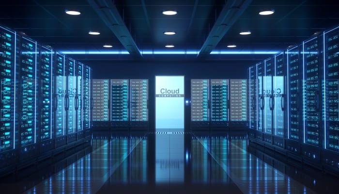 The interior of a data center with multiple rows of brightly-lit server racks and a door in the middle that says "Cloud".
